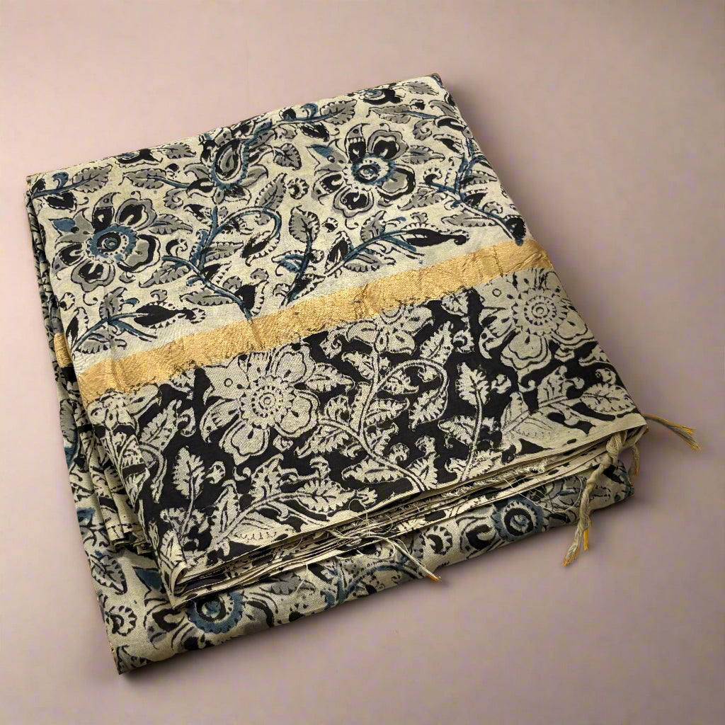 Folded fabric with black floral pattern on a light wooden surface with flowers in the corner.